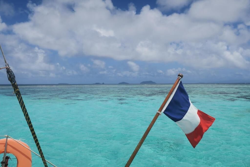 A flag on a boat in turquoise waters with a clear sky.