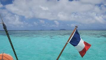 A flag on a boat in turquoise waters with a clear sky.