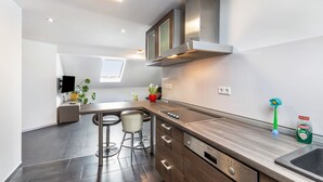 A modern kitchen with a built-in stove, bar stools, and a large window. - Holiday Apartment for Workers Near the Train Station (Babenhausen)