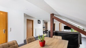 A modern dining area with a wooden table, chairs, and a red flower pot. - Holiday Apartment for Workers Near the Train Station (Babenhausen)