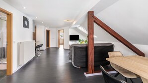A modern loft bedroom with a sloped ceiling, a wooden beam, a bed, a desk, and a chair. - Holiday Apartment for Workers Near the Train Station (Babenhausen)