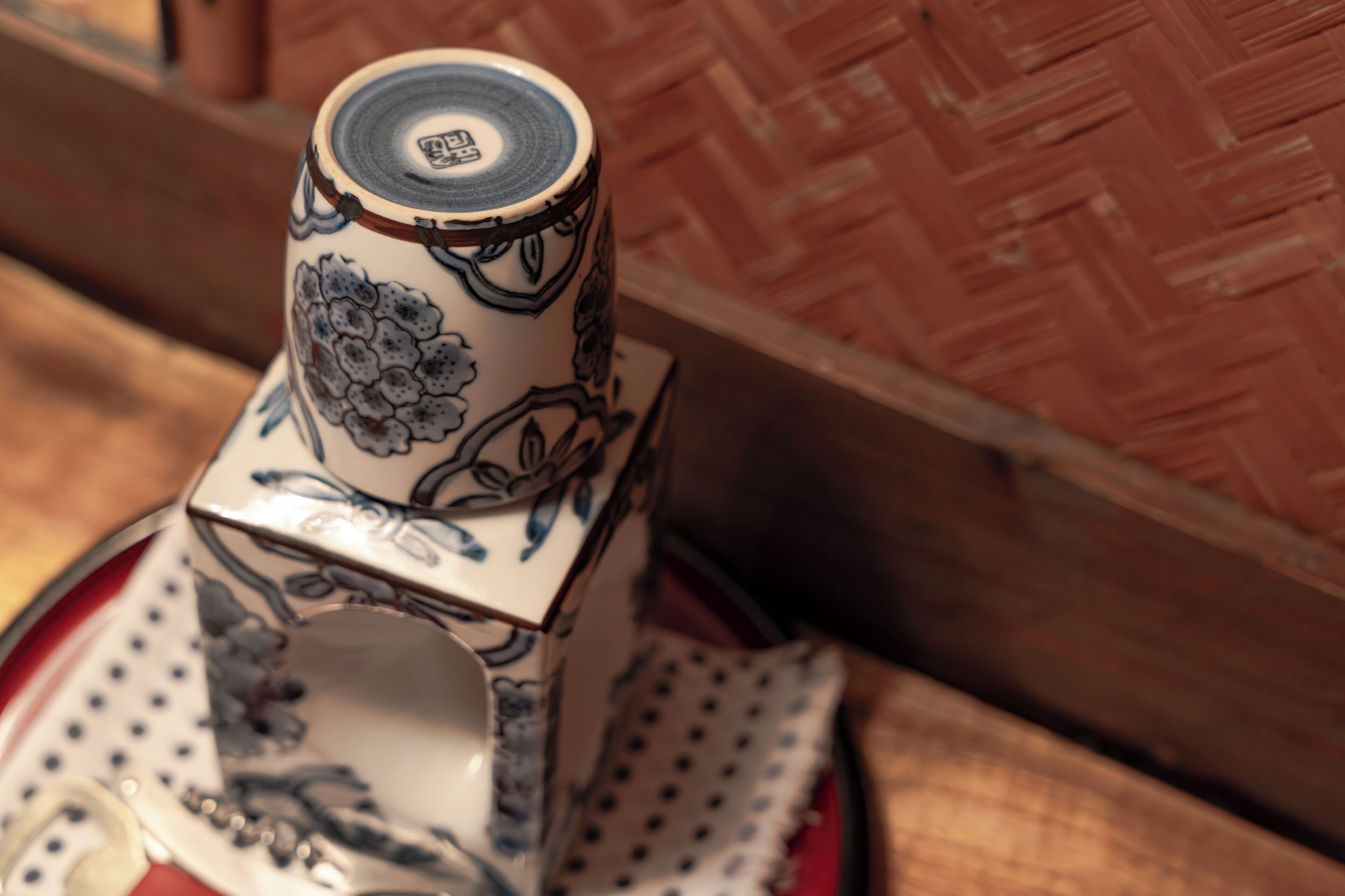 A ceramic teapot with floral designs, placed on a polka-dotted napkin.