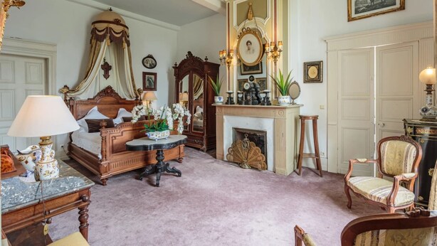 A bedroom with a four-poster bed, a fireplace, a mirror, and a chandelier. - Suite BORDEAUX park view (Hastingues)