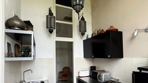 A compact kitchen with a sink, stove, and black cabinets. - Suite BORDEAUX park view (Hastingues)