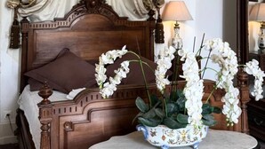 A bedroom with a canopy bed, a bedside table with a vase of flowers, and a mirror. - Suite BORDEAUX park view (Hastingues)