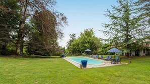A backyard with a swimming pool, lounge chairs, and umbrellas. - Suite BORDEAUX park view (Hastingues)