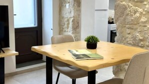 A small dining area with a wooden table, a single chair, a potted plant, and a book. - Nomas Home Kalyves • Beachfront Sea Views, Modern Comfort Steps from the Center (Chania)