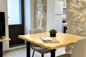 Un pequeño comedor con una mesa de madera, una silla, una planta en maceta y un libro.