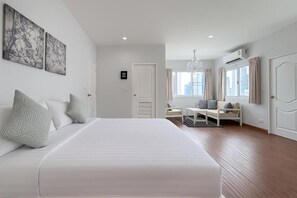 A modern hotel room with a large bed, a seating area with a table, and a view of the city through large windows. - Blissful Heaven Residence (Bangkok)