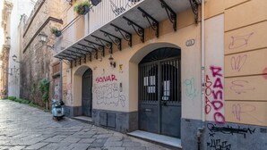 A narrow street with a building featuring a balcony, a door labeled 'POSTA,' and graffiti on the walls. - GuestHost - Cozy and comfortable 56 square meters apartment, perfect for four people, located on the first floor of a renovated period building with an elevator (NOT accessible to disabled guests).The property is located just steps from Palermo's histori (Palermo)