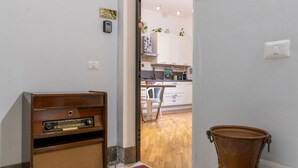 A room with a wooden radio, a door leading to a kitchen, and a vase on the floor. - GuestHost - Cozy and comfortable 56 square meters apartment, perfect for four people, located on the first floor of a renovated period building with an elevator (NOT accessible to disabled guests).The property is located just steps from Palermo's histori (Palermo)