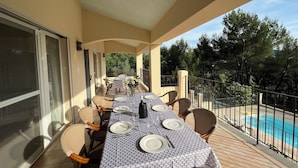 A covered outdoor dining area with a pool view, furnished with chairs and a table set for dining. - Villa with pool & large shaded terrace - Provence, absolute calm! (Mollans-sur-Ouvèze)