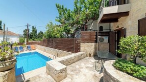 Area piscina con solarium in pietra, una piscina e un piccolo tavolo.