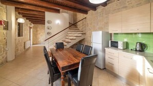 Un'ampia cucina con un tavolo da pranzo in legno, elettrodomestici moderni e una scala che conduce a un altro piano.