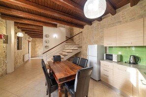 A spacious kitchen with a wooden dining table, modern appliances, and a staircase leading to another level. - 3-Min Drive to Kalyves Beach, Stone Home with Private Pool in Armenoi Center (Chania)