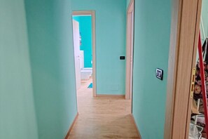 A narrow hallway with light-colored wooden flooring and teal walls. - Belvedere Home - Lake View with Terrace in the Center of Salò – Parking Space (Salò)