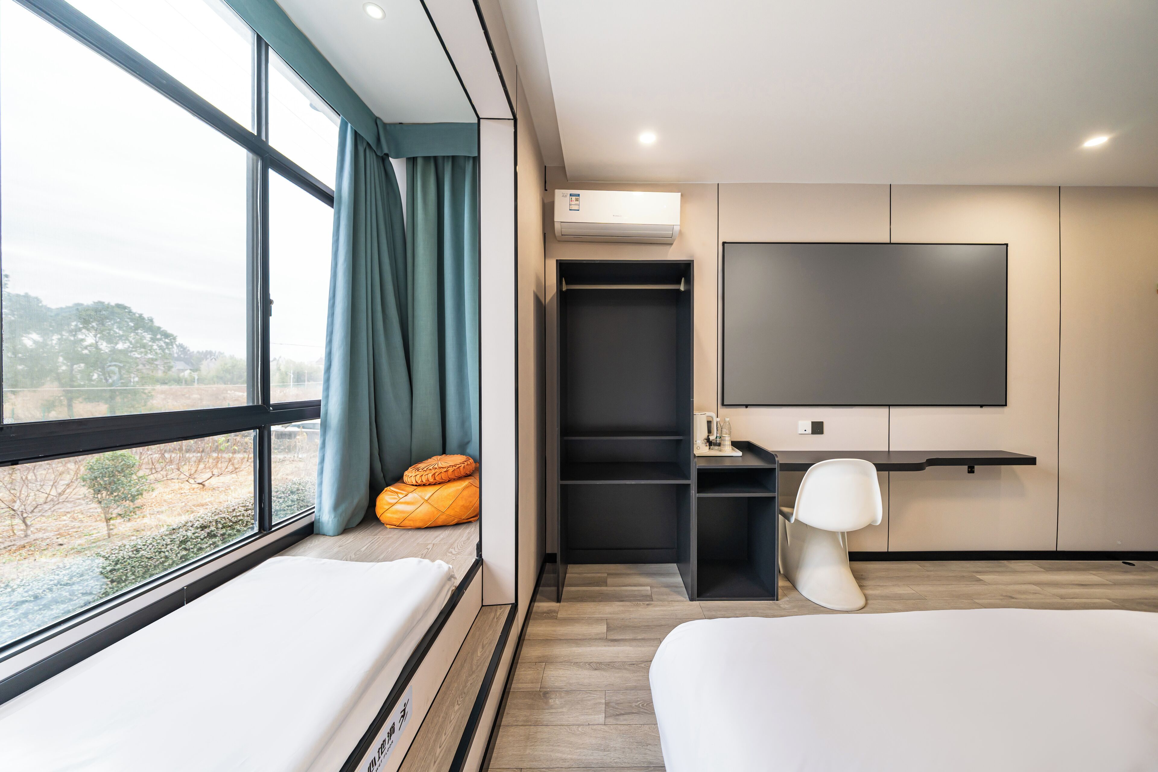 Ein modernes Hotelzimmer mit großem Fenster, einem Bett, einem Schreibtisch und einem Fernseher.