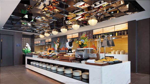 Un'area buffet con diverse postazioni di servizio, un'ampia scelta di cibi e interni moderni e ben illuminati.
