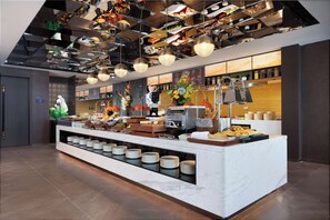 Un área de bufé con varias estaciones de servicio, una gran variedad de alimentos y un interior moderno y bien iluminado.