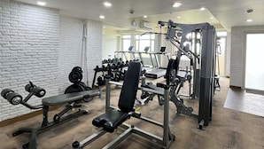 A gym with various exercise equipment, a white brick wall, and a wooden floor. - The Vineyard at Merlot TwinLakesTagaytay (Laurel)