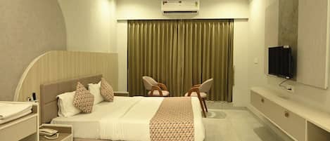 Ein modernes Hotelzimmer mit Bett, Schreibtisch, Stuhl, Fernseher und Klimaanlage.