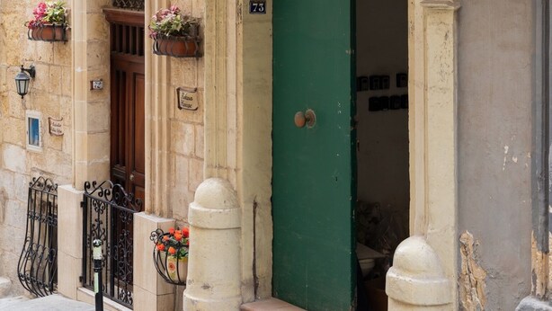 A historic building with a green door, ornate stone archways, and flower boxes. - Traditional APT with Internal Courtyard (Valletta)