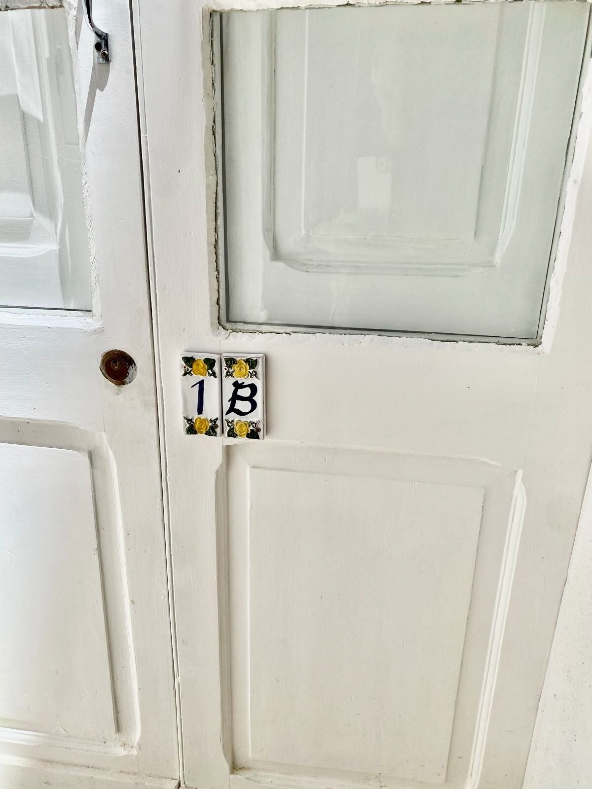 Une porte blanche avec une petite enseigne décorative au-dessus.