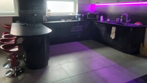 A modern kitchen with a black countertop, a window, and a purple under-cabinet lighting.