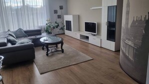 A modern living room with a sofa, coffee table, TV, and artwork on the wall.