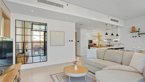 A modern living room with a sofa, coffee table, and a kitchen in the background. - Urban Chic 1 Bedroom w/ big Balcony Kitchen in JVC (Jumeirah Village Circle (JVC))
