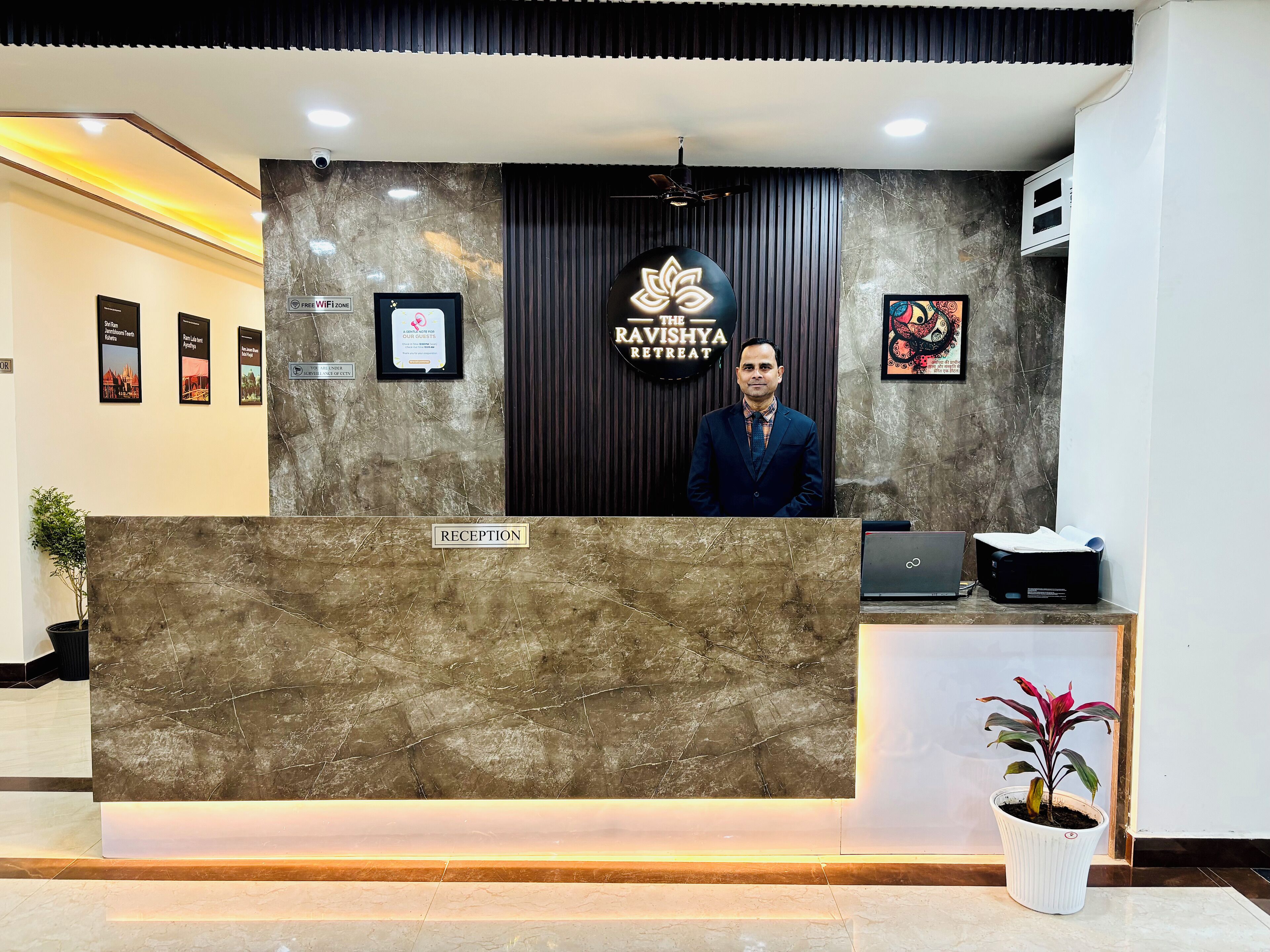 A reception desk with a marble top, a sign for "The Ravishya Retreat," and framed pictures on the wall.