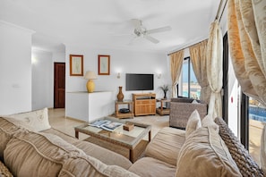 Ein Wohnzimmer mit Sofa, Couchtisch, Fernseher und Deckenventilator.