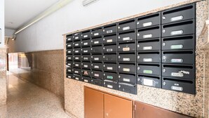 Une rangée de boîtes aux lettres avec des étiquettes, un comptoir en granit et un meuble brun.