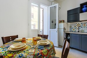 Ein Essbereich mit Tisch für vier Personen, eine Küche mit gefliestem Rückspritzschutz und eine Tür, die zu einem Außenbereich führt.