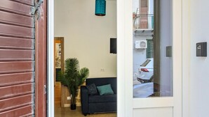 Una entrada que da a una sala de estar con un sofá, una planta en maceta y una lámpara colgante.