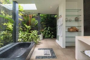 Une salle de bain moderne avec une douche à parois de verre, une baignoire et une étagère où sont rangées les serviettes et les articles de toilette.