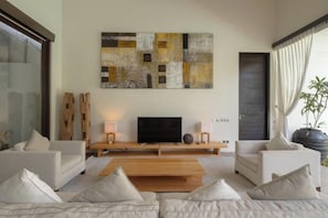 A modern living room with a flat-screen TV, a coffee table, and two sofas. - Villa Alice Satu (Bali)