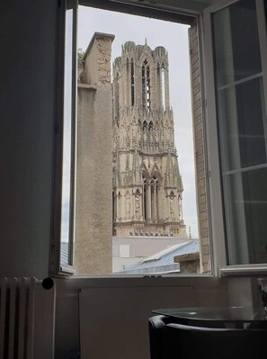 A view of a Gothic-style cathedral through a window, with a radiator and a chair visible inside. - REIMS - Apartment in an Art Deco building with a view of the cathedral - City center   (Reims)