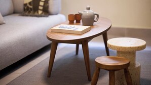 A small wooden table with a book, a teapot, and two cups on a carpeted floor. - Phaedrus Living: Kolonaki Crown Residences 1 (Athens)