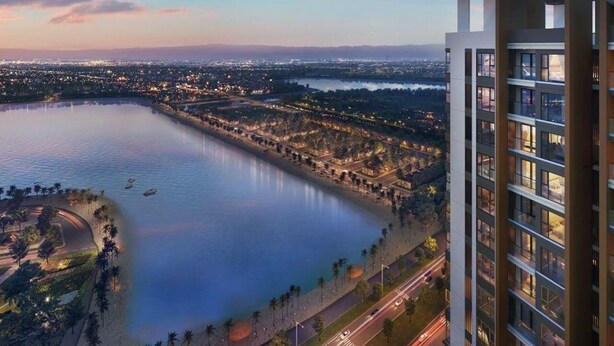 Een hoog hotel met uitzicht op een kalm wateroppervlak en een stadsgezicht op de achtergrond.