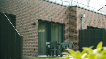 A brick building with a patio area, including a table and chairs, and a fenced garden.