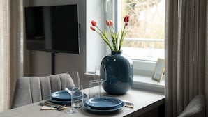 Ein Esstisch ist gedeckt mit Tellern, Gläsern und einer Blumenvase.