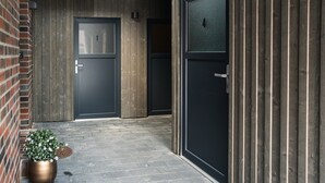 Un estrecho pasillo con dos puertas, una con el número 1 y otra con el número 4, que conduce a un muro de ladrillo y un panel de madera.