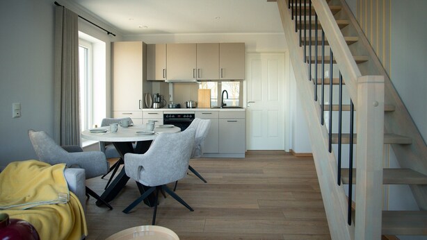 Una cocina moderna con comedor, piso de madera y una escalera.