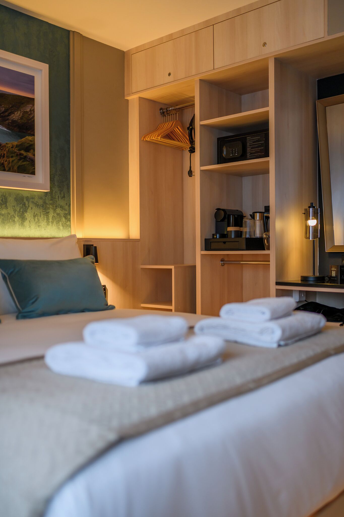 A hotel room with a bed, a wardrobe, a desk, and a mirror.