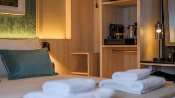 Una habitación de hotel con cama, armario, escritorio y espejo.