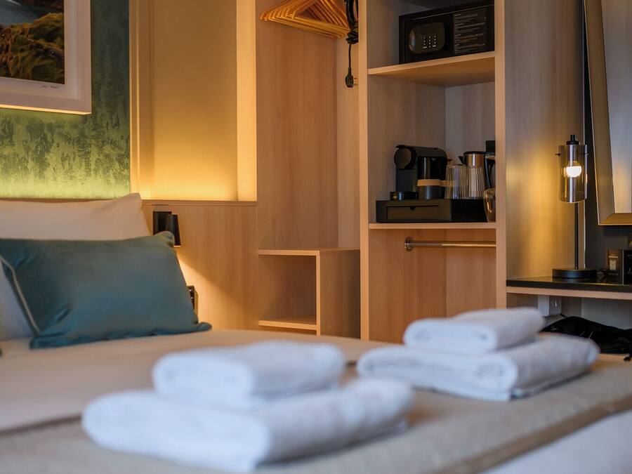 Una habitación de hotel con cama, armario, escritorio y espejo.