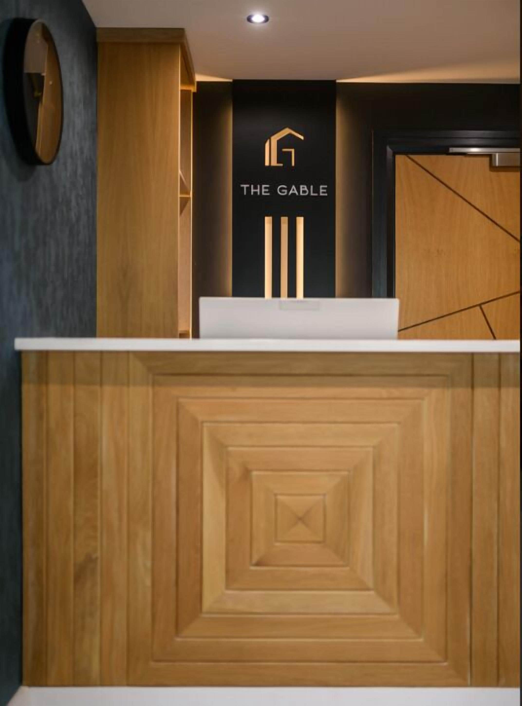 A reception desk with a logo, a wooden panel design, and a dark wall.