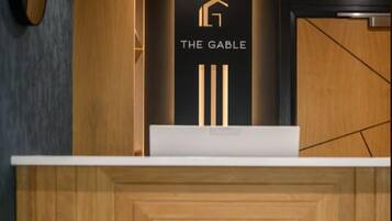 A reception desk with a logo, a wooden panel design, and a dark wall.