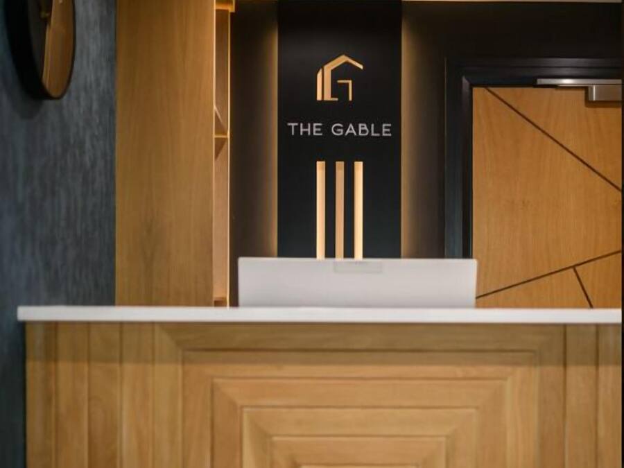 Un mostrador de recepción con un logotipo, un diseño de paneles de madera y una pared oscura.